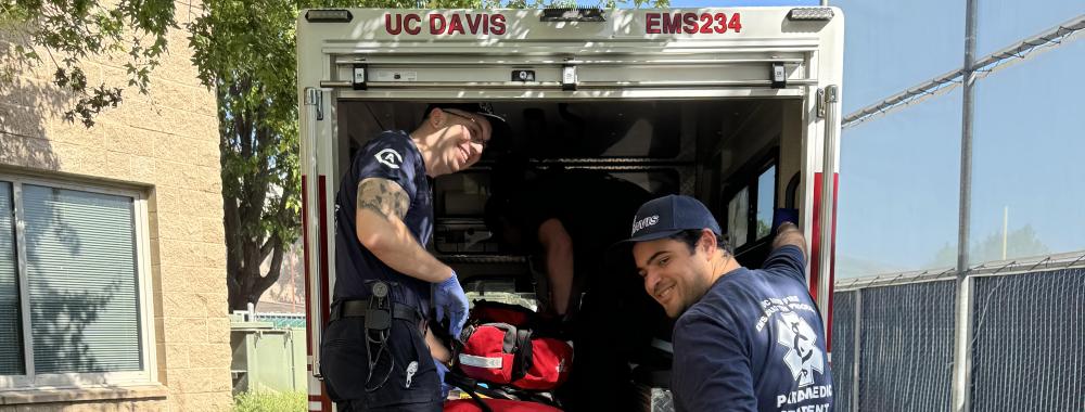 Paramedic students smile while in the back of an ambulance.