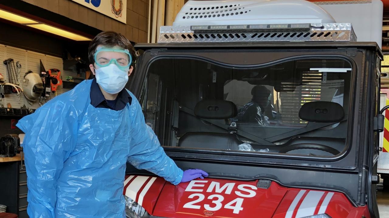 Student EMT Matt Kenaston stands beside EMS 234, the vehicle used by UC Davis Fire to transport COVID positive and close contact students to quarentine student housing.