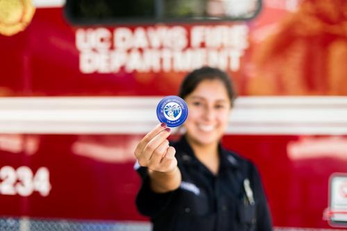 UC Davis Student EMT holding a CPR certification sticker.