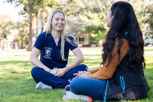 A Health 34 provider listens to a student while they sit in the grass.