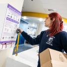 An EMT in a UC Davis shirt with a box of supplies, unlocks the Narcan cabinet in the Memorial Union