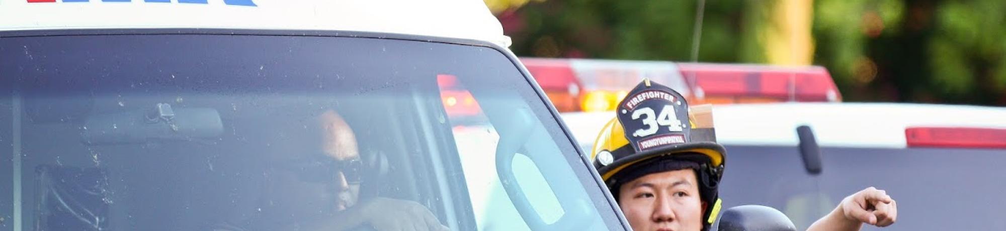 I firefighter provides direction to an ambulance at an emergency scene.