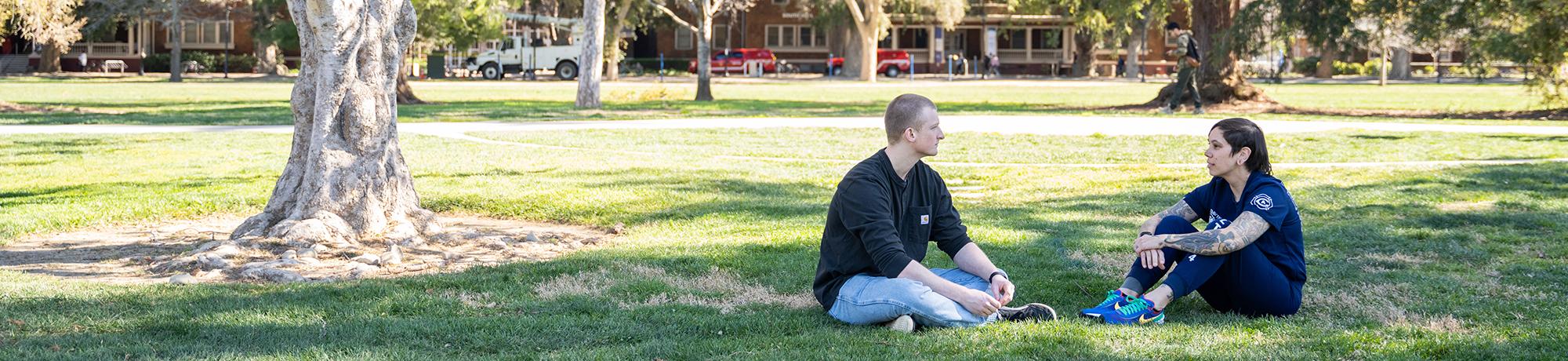 Health 34 employee sitting and talking with student on campus
